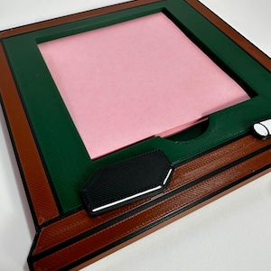 Puede incluir: Un marco cuadrado multicolor con interior verde, exterior marrón y detalles en negro. El marco contiene un cuadrado rosa. El marco tiene un diseño único con una pieza de acento en blanco y negro.