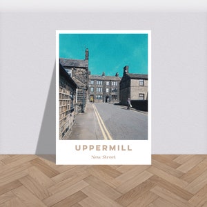 Puede incluir: Un póster de estilo vintage con una foto de una calle estrecha en un pueblo con edificios de piedra. La calle está bordeada de edificios a ambos lados y tiene un cielo azul arriba. El texto "UPPERMILL New Street" está en la parte inferior del póster.