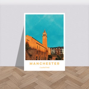 May include: A vintage-style poster with a photograph of a tall brick building with a tower in Manchester, England. The poster has a blue sky background and the text "MANCHESTER" and "Castlefield" in orange.