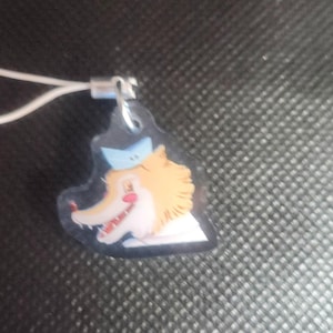 Könnte beinhalten: Ein kleiner, klarer Acryl-Anhänger mit einem Cartoon-Fuchs-Charakter mit orangefarbenem Fell, einem blauen Hut und einem roten Mund. Der Anhänger ist an einer weißen Schnur und einem silberfarbenen Metallverschluss befestigt.