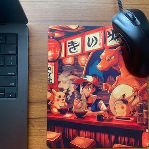May include: Rectangular mousepad featuring a vibrant anime-style illustration of characters eating ramen in a Japanese restaurant. The design includes a laptop and a black mouse. The mousepad has a red and brown color scheme.