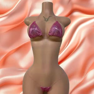 May include: Pink sparkly bikini top and bottom with clear straps. The top is a triangle style and the bottom is a thong style.