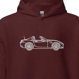 Puede incluir: Una sudadera con capucha color burdeos con un contorno blanco de un coche descapotable en la parte delantera.