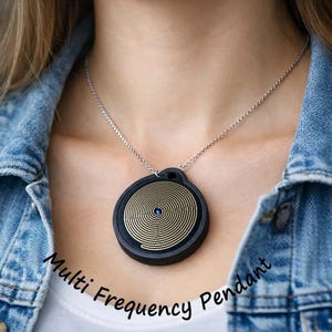 May include: A black pendant with a gold spiral design and a small blue gem, suspended from a silver chain. The pendant is circular and has the words "Multi Frequency Pendant" in white script.
