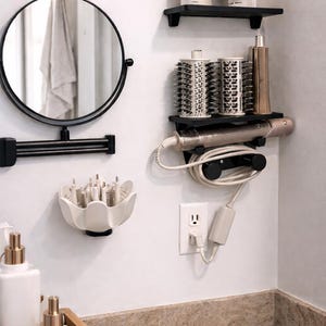 Puede incluir: Una moderna configuración de baño con un espejo redondo con marco negro, un secador de pelo montado en la pared y varias herramientas de peinado. La imagen muestra un espacio limpio y organizado con paredes blancas y estantes negros, ideal para el cuidado del cabello.
