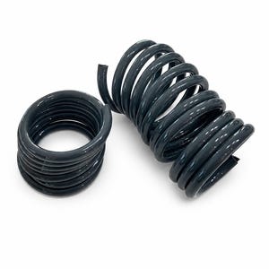 May include: Two dark grey, glossy, coiled metal springs. One spring is positioned vertically in a tight, cylindrical spiral shape, while the other is laid horizontally, showing a circular opening through the centre of the coiled wire structure.