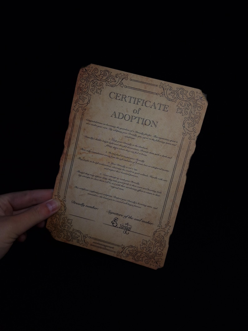 Puede incluir: Un Certificado de Adopci&oacute;n de estilo vintage con bordes ornamentados y texto. El documento tiene un tono sepia, con el t&iacute;tulo "Certificado de Adopci&oacute;n" en la parte superior. Incluye l&iacute;neas para detalles y una firma.