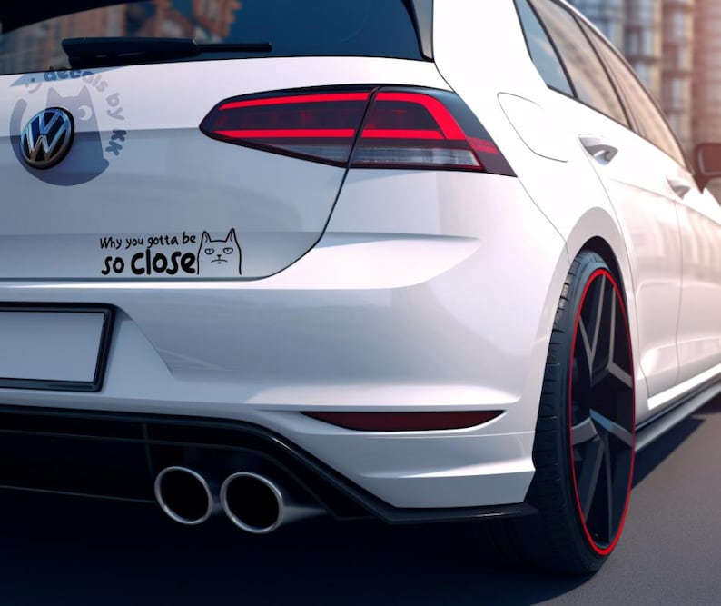 May include: White car with a black and white cat sticker on the rear bumper. The sticker says "Why you gotta be so close".