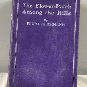 May include: A purple hardcover book titled "The Flower-Patch Among the Hills" by Flora Klickmann.