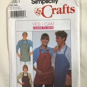 May include: Simplicity Crafts sewing pattern for a simple apron. The pattern includes instructions for making three different aprons: a red and white floral apron, a blue denim apron, and a brown apron. The pattern is titled "Yes I Can Learn to Sew".