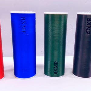 May include: Four cylindrical containers with white tops and different colors: red, blue, green, and black. Each container has the text "BXMP" printed on the side.