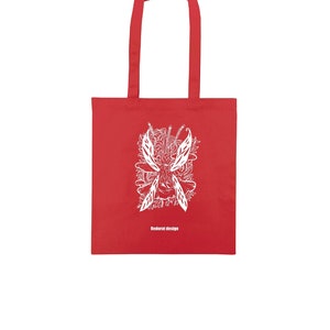 Puede incluir: Bolsa de tela roja con un gráfico blanco de un hada con alas y el texto "Redorat design".