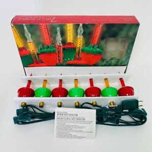 Op de afbeelding: Een vintage kerstverlichtingsset met zeven multi-bubble lampjes. De lampjes zijn rood, groen en geel, met een groen snoer en een doos met een feestelijk ontwerp. Op de doos staat "7 Multi Bubble Light Set".