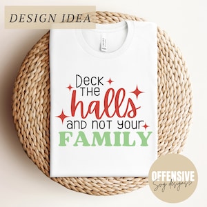 Puede incluir: Camiseta blanca con texto rojo y verde que dice "Deck the halls and not your family". El texto está rodeado de pequeñas estrellas. La camiseta está sobre una superficie tejida.