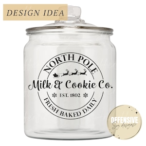 Op de afbeelding: Een glazen koekjespot met een transparant ontwerp met een zwart-wit ontwerp dat "North Pole Milk & Cookie Co. Est. 1802 Fresh Baked Daily" zegt. Het ontwerp bevat een silhouet van Sinterklaas in zijn slee met rendieren.