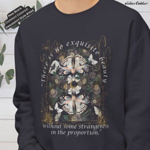 May include: A dark gray sweatshirt with a graphic print of butterflies, flowers, and a crescent moon. The text "There is no exquisite beauty without some strangeness in the proportion." is printed on the sweatshirt.