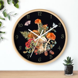 May include: A round clock with a black background and white clock hands. The clock face features a design of mushrooms, leaves, and butterflies in shades of brown, red, and green. The numbers 1 through 12 are displayed in a gold font.