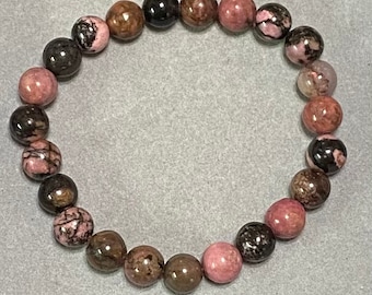 May include: A pink, brown, and black gemstone bracelet with round beads.