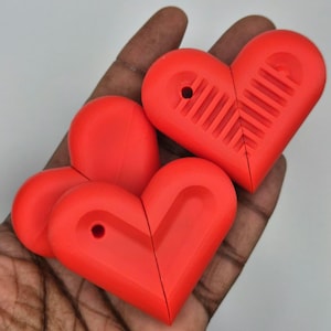 Puede incluir: Varios objetos en forma de coraz&oacute;n de color rojo brillante se sostienen en una mano. Cada uno tiene un agujero y un dise&ntilde;o acanalado. Los objetos parecen estar hechos de pl&aacute;stico o un material similar. Los objetos son de un color rojo vibrante.
