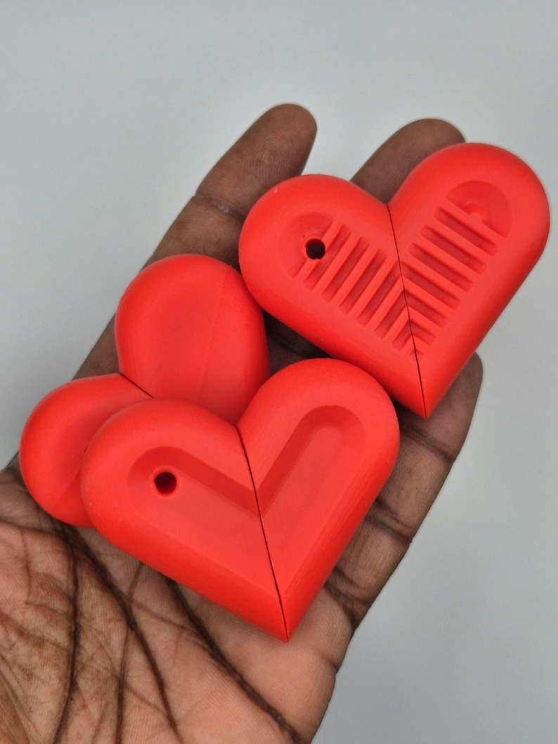 Puede incluir: Varios objetos en forma de coraz&oacute;n de color rojo brillante se sostienen en una mano. Cada uno tiene un agujero y un dise&ntilde;o acanalado. Los objetos parecen estar hechos de pl&aacute;stico o un material similar. Los objetos son de un color rojo vibrante.