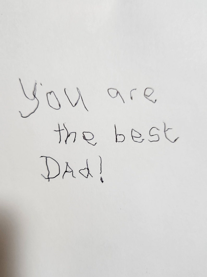 Op de afbeelding: Handgeschreven notitie op wit papier met de tekst "You are the best Dad!"