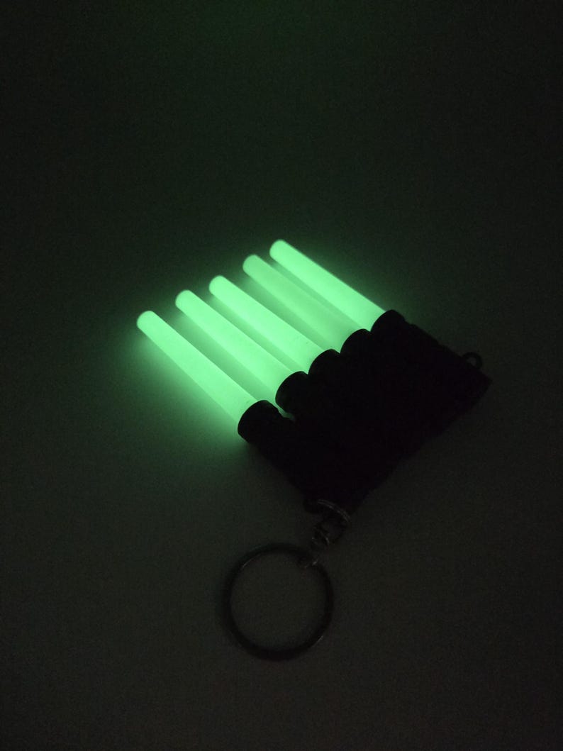 K&ouml;nnte beinhalten: Ein Set aus f&uuml;nf leuchtend gr&uuml;nen Leuchtst&auml;ben, die an einer schwarzen Basis mit einem Schl&uuml;sselring befestigt sind. Die zylindrischen Leuchtst&auml;be strahlen hellgr&uuml;nes Licht aus. Der Hintergrund ist dunkel.