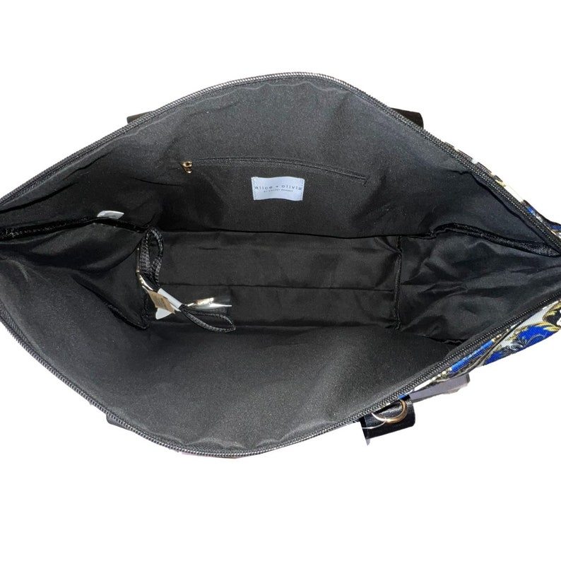 Puede incluir: El interior de una bolsa de mano negra con un forro estampado en azul y dorado. La bolsa tiene un cierre de cremallera y un peque&ntilde;o bolsillo en el interior. La etiqueta en el interior de la bolsa dice "Willow & Blake, Designed in New York."