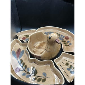 May include: A ceramic serving dish set featuring a bird-shaped bowl in the centre. The dish is decorated with a floral pattern in shades of brown, green, blue, and red.