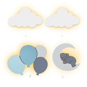 May include: Four different wall light fixtures with a nursery theme. The first two are white clouds with a yellow glow. The third is a cluster of three blue and grey balloons with a yellow glow. The fourth is a white crescent moon with a sleeping grey elephant inside and a yellow glow.