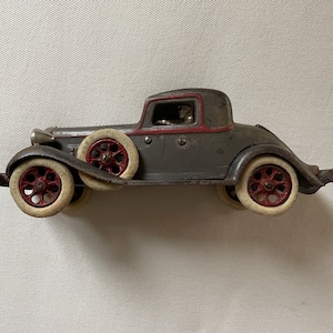 Arcade REO rumble seat coupe cast iron toy car and driver, with side mount spare tires
