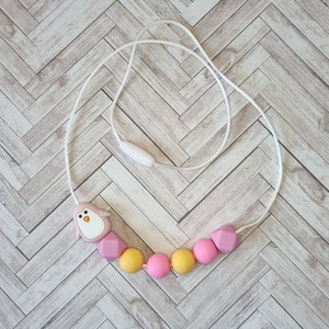 Puede incluir: Un collar de dentici&oacute;n de silicona rosa y amarillo con un dije de ping&uuml;ino. El collar est&aacute; hecho de cuentas de silicona suaves y masticables y est&aacute; dise&ntilde;ado para beb&eacute;s y ni&ntilde;os peque&ntilde;os.