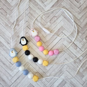 Puede incluir: Tres collares de dentici&oacute;n de silicona con dijes de ping&uuml;ino. Los collares est&aacute;n hechos con cuentas de diferentes colores, incluyendo amarillo, rosa, azul, blanco y negro.