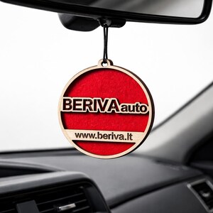 Puede incluir: Un ambientador de coche redondo con marco de madera y centro rojo. El texto "BERIVA auto" y el sitio web "www.beriva.lt" son visibles. Cuelga de una cuerda negra.