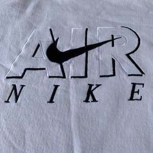 May include: White hooded sweatshirt with a black embroidered Nike logo and the word "AIR" in white with black outlines.