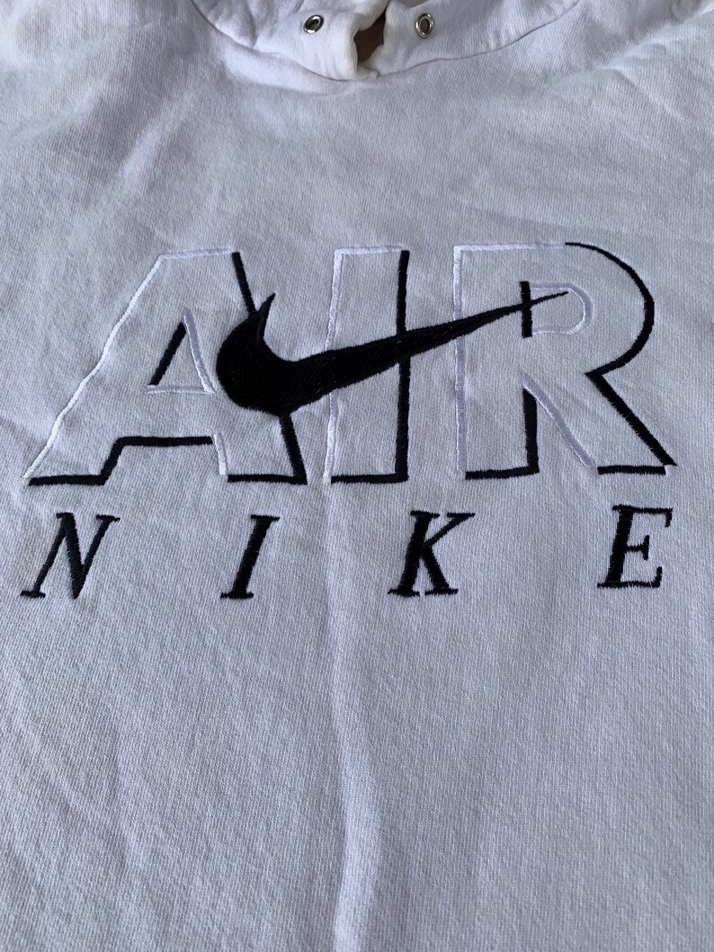 May include: White hooded sweatshirt with a black embroidered Nike logo and the word "AIR" in white with black outlines.