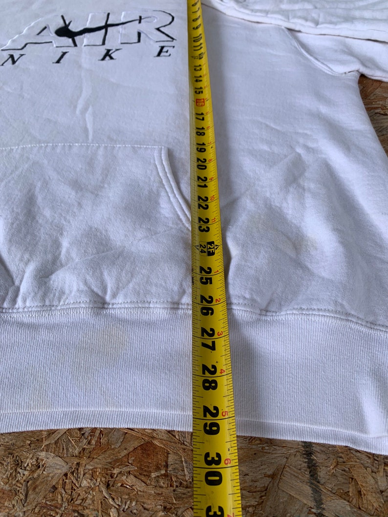 May include: White hoodie with a black Nike logo and the word "AIR" in white lettering. The hoodie is measured with a tape measure, showing a length of 29 inches.