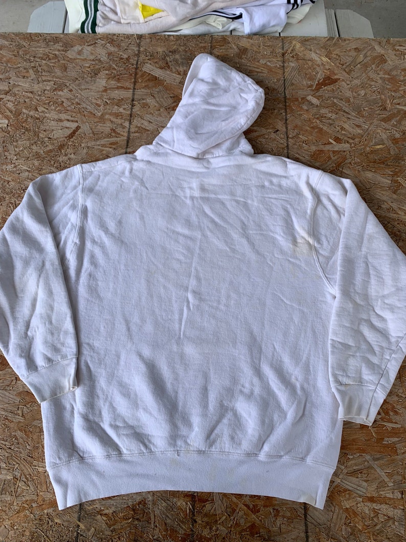 May include: A white hooded sweatshirt with a drawstring hood. The sweatshirt is made of a soft, comfortable fabric and has a relaxed fit.