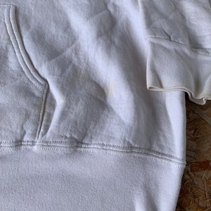 May include: White hooded sweatshirt with a pouch pocket. The sweatshirt has a ribbed hem and cuffs.