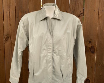 May include: A light beige leather jacket with a zipper closure and a small embroidered logo on the left chest.