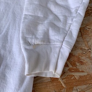 May include: White long-sleeved sweatshirt with a ribbed cuff. The sweatshirt is made of a soft, comfortable fabric.