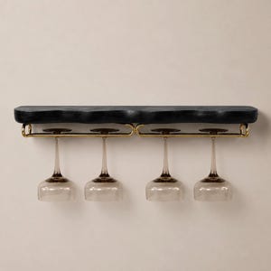May include: A wall-mounted shelf featuring a thick, black, textured wooden top with an irregular edge. Attached to the underside is a gold-toned metal rack designed to hold four stemmed wine glasses, which are hanging upside down by their bases.