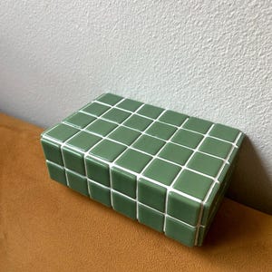 May include: A green rectangular box made of small square tiles. The tiles have white grout lines.