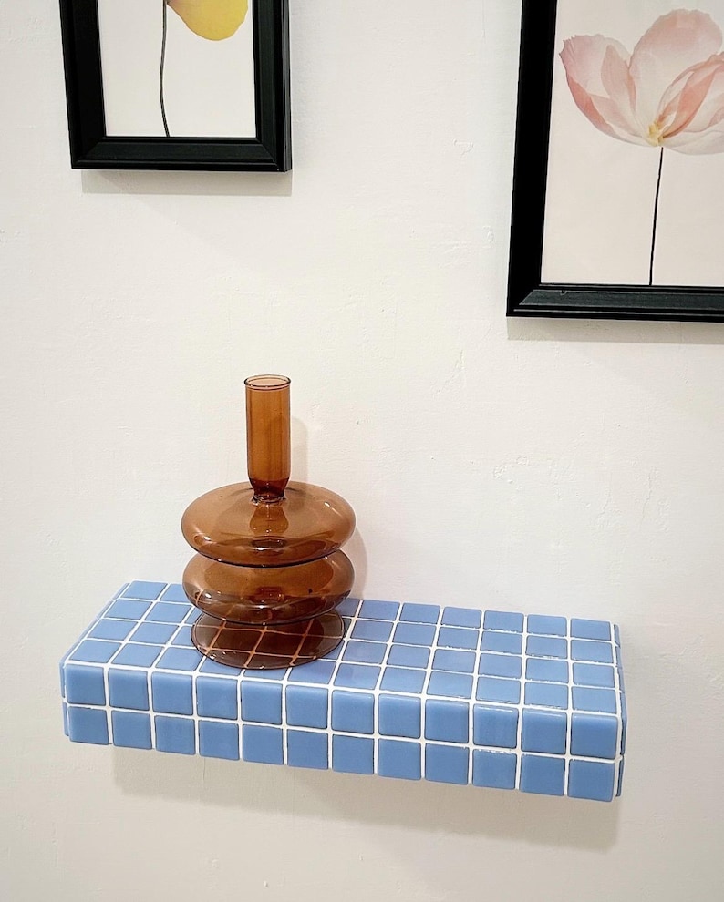 Puede incluir: Una estanter&iacute;a de azulejos azules con un jarr&oacute;n de vidrio marr&oacute;n en la parte superior. El jarr&oacute;n tiene una forma redonda y bulbosa y est&aacute; hecho de tres piezas apiladas.