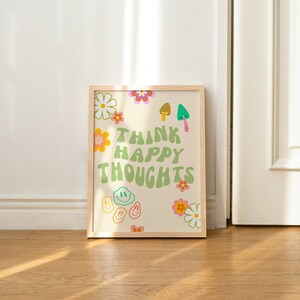May include: A framed print with a white background and green text that reads "Think Happy Thoughts". The print is decorated with colorful flowers, smiley faces, and mushrooms.