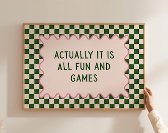 Puede incluir: Un cuadro rectangular enmarcado en madera con un patrón de tablero de ajedrez en verde oscuro y crema. En el centro, un rectángulo rosa claro de bordes ondulados contiene el texto en verde oscuro: ACTUALLY IT IS ALL FUN AND GAMES.