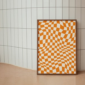 May include: A framed print with a checkered pattern in orange and white. The pattern is distorted to create a wavy, optical illusion effect.
