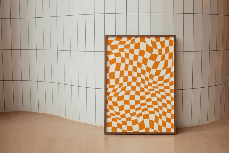 May include: A framed print with a checkered pattern in orange and white. The pattern is distorted to create a wavy, optical illusion effect.