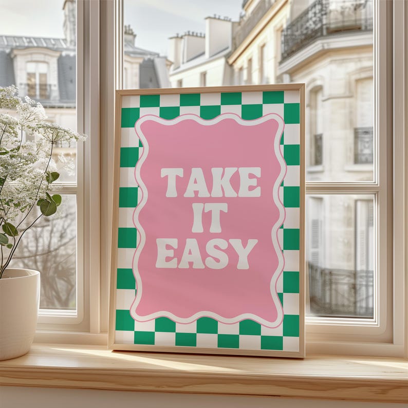 May include: A framed print with a pink background and white text that reads "Take it easy". The background is a green and white checkered pattern.
