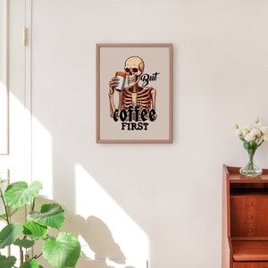 May include: A framed print featuring a cartoon skeleton holding a cup of coffee with the text "But coffee first".