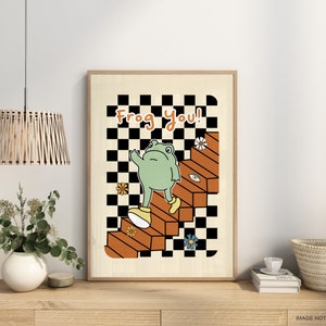 May include: A framed print featuring a green frog ascending a set of stairs against a checkered backdrop. The text "Frog You!" is displayed at the top of the print.